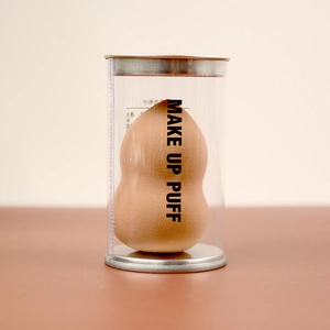 Detail of nude gourd makeup puff in clear case with metallic base and lid