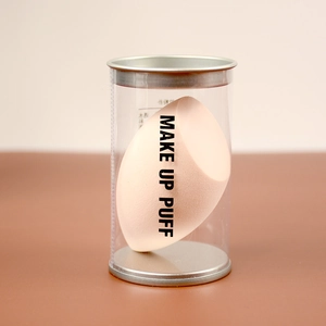 Macro shot of a peach-colored makeup puff in a clear plastic tube with metal lid