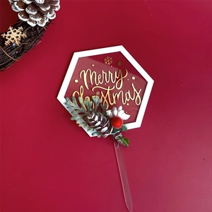 Detail of hexagonal acrylic Merry Christmas cake topper with red berries and pine cones
