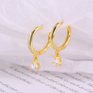 Detailed macro of gold-plated silver hoop earrings with clear round cubic zirconia drops