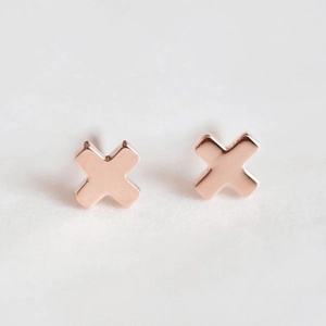 Vue macro de boucles d'oreilles croix or rose avec finition polie et design en X