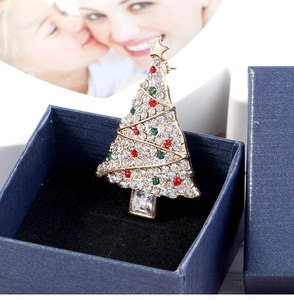 Close-up of golden Christmas tree brooch with colorful rhinestones in a blue gift box