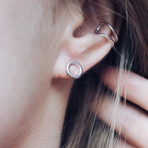 Close-up of minimalist silver stainless steel hoop earring and double-line ear cuff on ear
