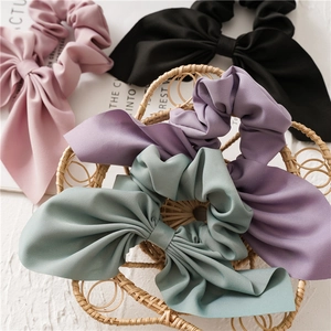 Detail of bunny ear scrunchies with long ribbons in four colors on a textured tray