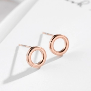 Macro view of minimalist hollow geometric rose gold circle stud earrings on white backdrop
