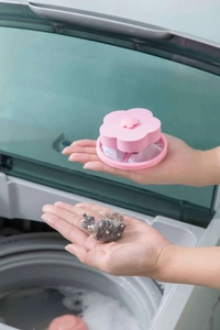 Pink plum-shaped washing machine filter showing captured lint and hair debris