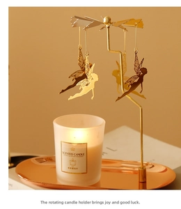 Detailed view of golden rotating candle holder with fairy pendants and frosted candle jar