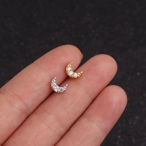 Macro shot of gold and silver moon-shaped stud earrings with zircons on a finger
