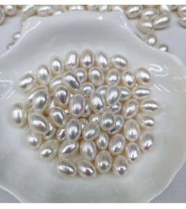 Detailed view of 7.5-8mm oval freshwater pearls in a white shell dish with glossy luster