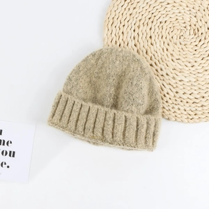 Detailed close-up of thick beige knit beanie with ribbed cuff and soft wool texture