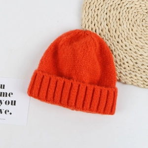 Detailed close-up of bright orange knitted beanie with thick ribbed cuff and soft texture