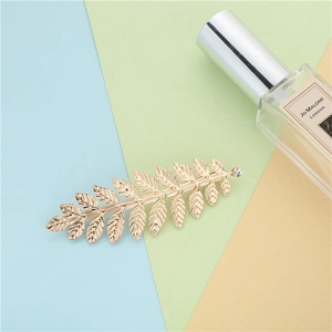 Barrette dorée en forme de feuille avec cristal sur fond géométrique coloré