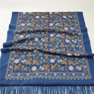 Close-up of blue cashmere-like scarf showing exquisite floral embroidery and tassel fringe