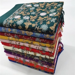 Detailed view of stacked cashmere-feel scarves with exquisite floral embroidery and tassels