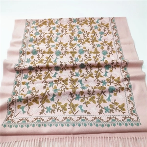 Close-up of pink cashmere-like shawl featuring intricate floral embroidery and tassel fringe