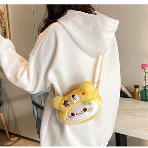 Détail du sac à bandoulière ours en peluche jaune porté sur un sweat à capuche blanc au café