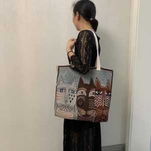 Detail of canvas tote bag featuring artistic cat faces print worn by a model