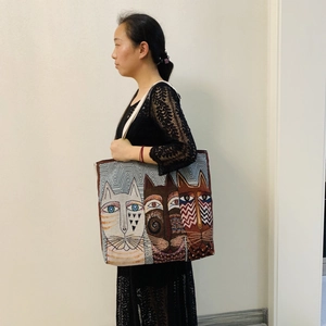 Canvas tote bag detail with artistic cat print worn by model over a black lace dress