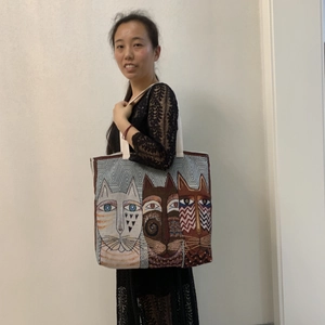 Lifestyle shot of large canvas cat tote bag worn by model against plain wall
