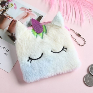 Plush unicorn coin purse in white and blue with purple sequin horn on a cozy pink background