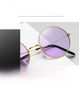 Detail of round sunglasses with light purple lenses and high-quality gold metal frame