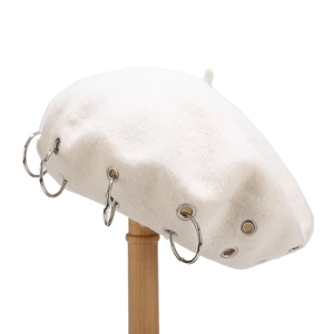 Detailed macro view of white wool beret with punk style silver metal ring embellishments