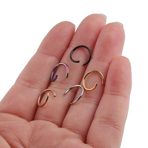 Close-up of 10mm stainless steel open rings in five colors held on a palm for size reference