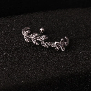 Dettaglio macro di piercing helix in acciaio inossidabile argento con zircone foglia e fiore