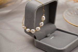 Baroque pearls and gold beads necklace detail inside a grey velvet jewelry box