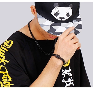 Close-up of men wearing a black curb chain necklace and a black dragon head design bracelet