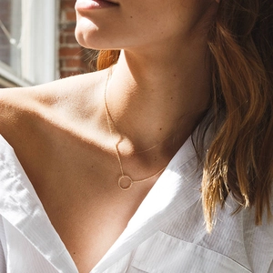 Detailed view of a minimalist gold geometric ring pendant on a delicate chain necklace