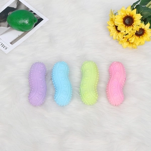 Peanut-shaped rubber dog chew toys in pastel colors on soft plush background
