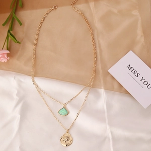 Detail of double-layer gold chain with turquoise pendant and portrait coin on silk