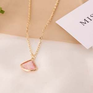 Detalle de un collar dorado con un colgante en forma de abanico e incrustación de opalo rosa