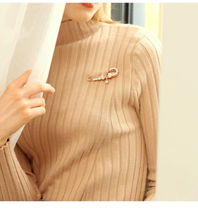 Detailed view of scorpion brooch with sparkling rhinestones on brown knitted sweater