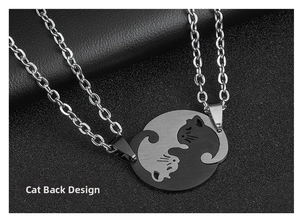 Macro detail of brushed metal cat pendants on black leather showing the back design