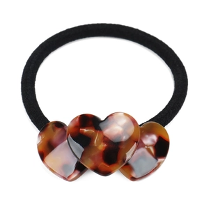 Detail shot of heart-shaped acetate charms with tortoiseshell patterns on black hair tie