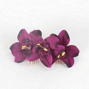 Detail of purple silk orchid flowers with black edges on a golden metal hair comb
