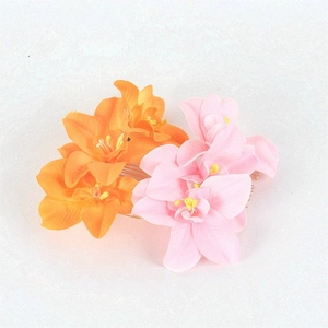 Detailed view of handmade silk orchid flower hair combs in orange and pink with gold teeth
