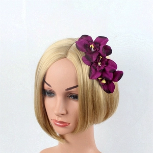 Detail of dark purple orchid hair comb with three flowers on a golden hair stylist model