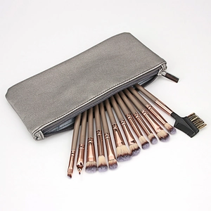 Macro shot of 13 makeup brushes with rose gold ferrules and a silver PU travel bag