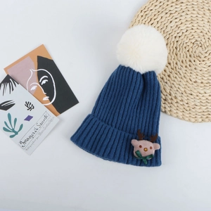 Détail du bonnet de Noël en tricot bleu marine avec pompon blanc et figurine de renne