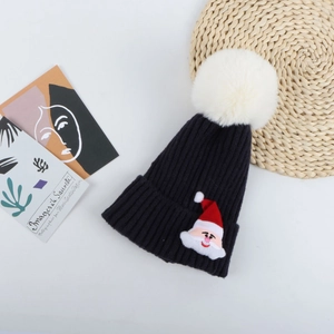 Broderie détaillée du Père Noël sur un bonnet en tricot bleu marine avec pompon blanc