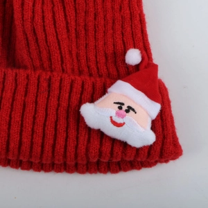 Détail d'un bonnet de Noël en maille côtelée rouge avec un joli écusson du Père Noël