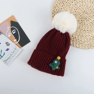Détail du bonnet de Noël bordeaux en maille avec pompon blanc et motif sapin