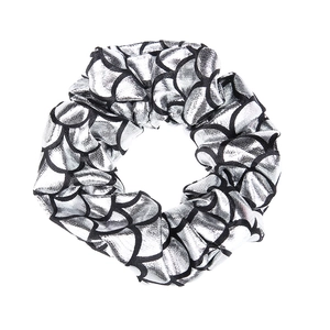 Close-up of a shimmering silver and black mermaid scale patterned fabric scrunchie