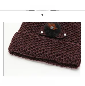 Detailed view of dark red knit beanie featuring a faux fur pompom and rhinestone accents