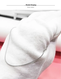 Dettaglio di una collana a sfere in argento sterling 925 tenuta con guanti bianchi