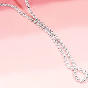 Macro di una catena a sfere in argento sterling 925 con finitura lucida su sfondo rosa