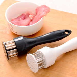 Close-up of black and white meat tenderizer needles on a wooden cutting board